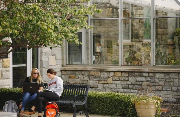 students on campus near greenhouse